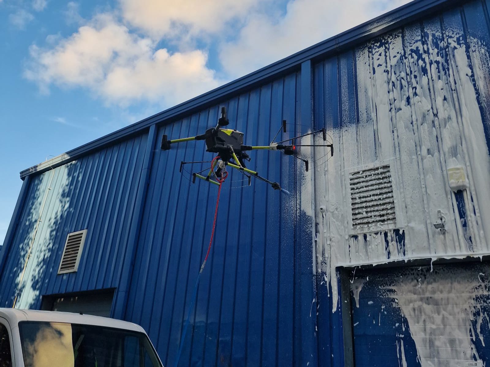 Dron myjący elewację blaszaną hali z użyciem piany