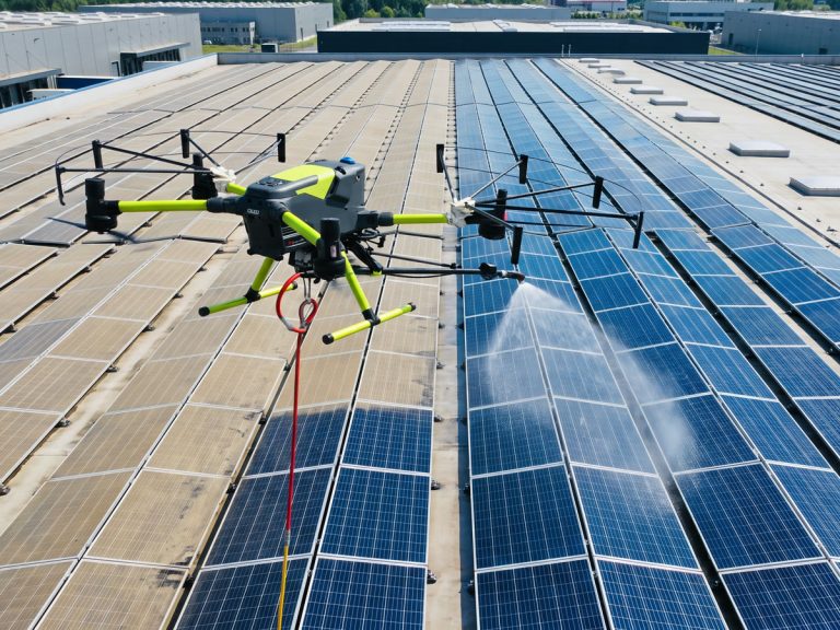 Dron myjący panele fotowoltaiczne na dachu hali